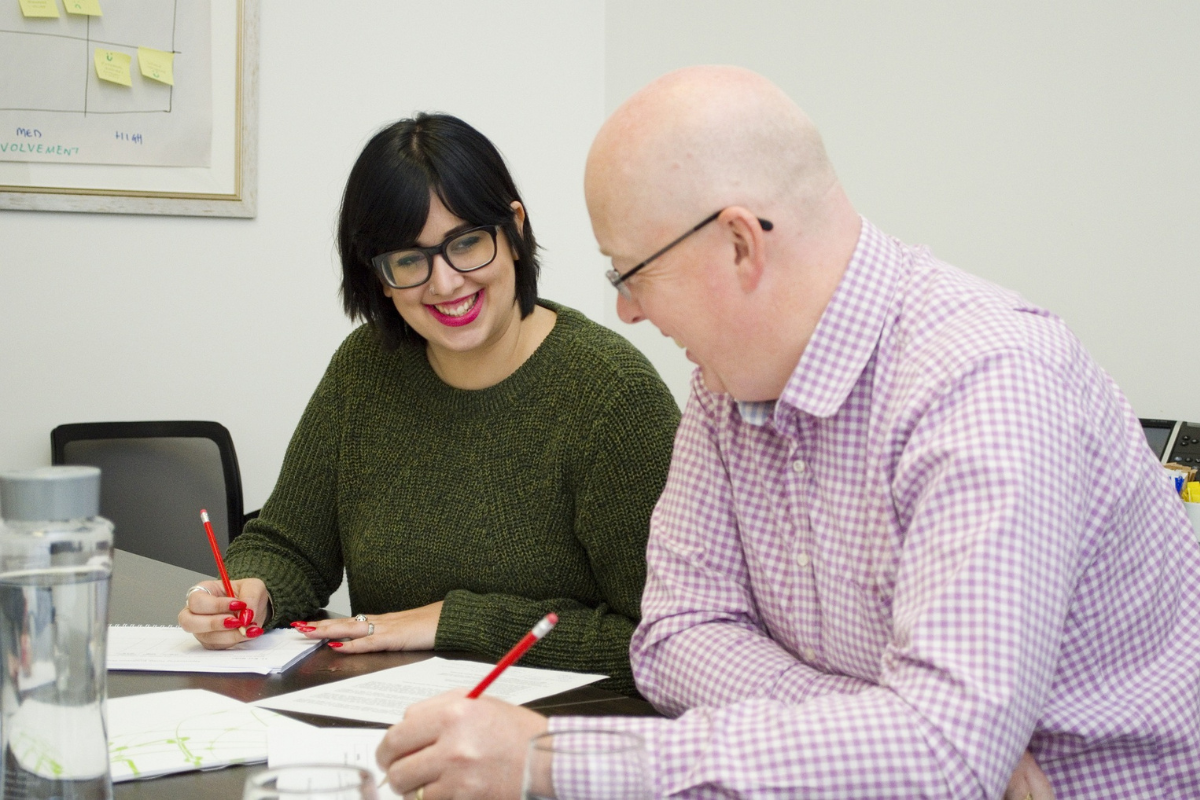 man and woman smiling and writing on paper