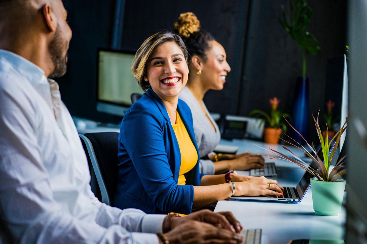 woman sitting at desk smiling at person sitting beside her