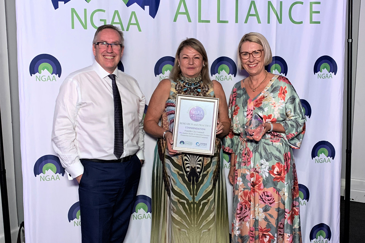 three people standing in a line holding a certificate