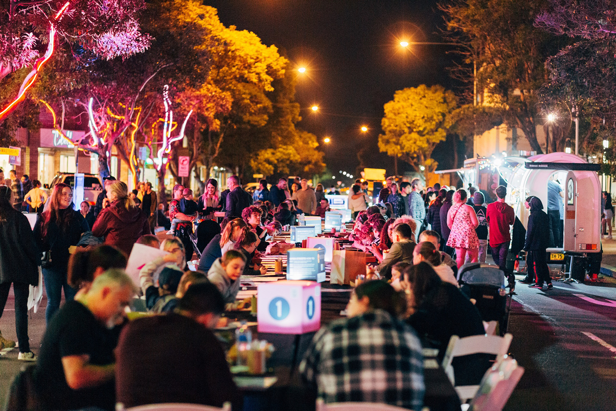 large group of people eating at long table at night